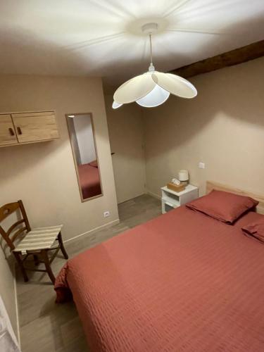 a bedroom with a red bed and a ceiling fan at Le Marlo in Poilley