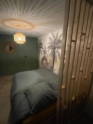 a bed in a bedroom with a wall with palm trees at Le Marlo in Poilley