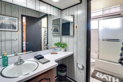 uma casa de banho com um lavatório, um espelho e uma banheira em Gouldsboro Cabin with Game Room - Near Lakes! em Gouldsboro