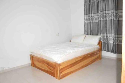 a wooden bed in a room with a window at Gloryphil House in Lomé