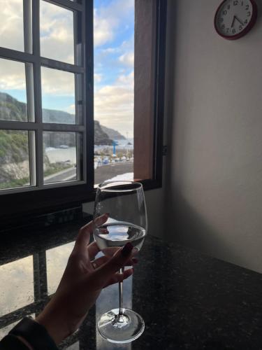 una persona sosteniendo una copa de vino frente a una ventana en Apartamento El Mar en San Andres y Sauces