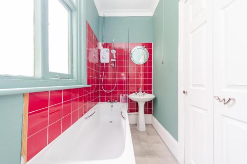 a bathroom with pink tiles and a sink and a tub at Stunning STUDIO Apartment in Hove Minuets away to BRIGHTON BEACH in Brighton & Hove