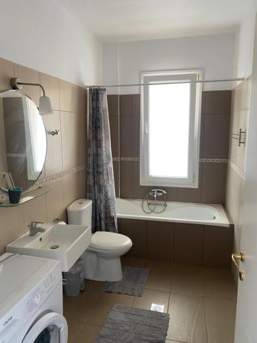a bathroom with a sink and a toilet and a window at VILLA ARMONIA GUEST HOUSE in Prinos