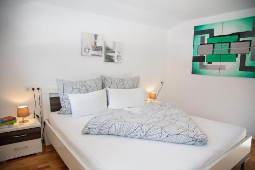 1 cama blanca en un dormitorio con una pintura en la pared en Ferienhaus Hochvogel en Hinterhornbach