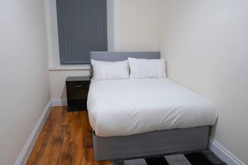 uma cama com lençóis brancos e almofadas num quarto em Glasgow - 2 Bedroom Apartment em Glasgow