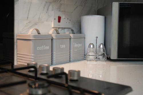 a kitchen counter with several dishes and a microwave at Glasgow - 2 Bedroom Apartment in Glasgow