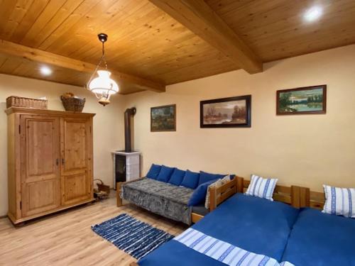 a living room with a blue couch and a wooden ceiling at Chalupa u babky in Ružomberok