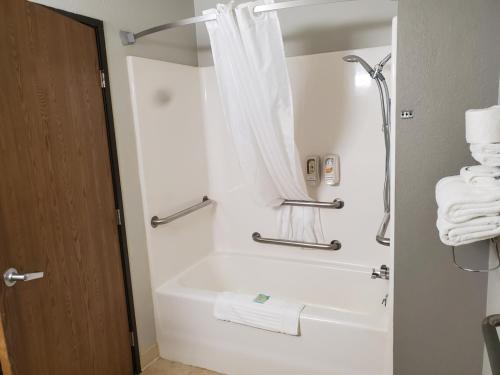 a bathroom with a tub and a shower with towels at Hibbing Inn & Suites in Hibbing