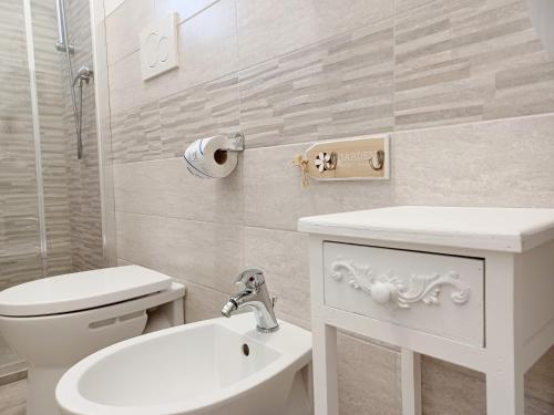 a white bathroom with a sink and a toilet at Il Giardino in Riotorto