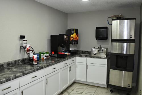 a kitchen with white cabinets and a black refrigerator at Hibbing Inn & Suites in Hibbing