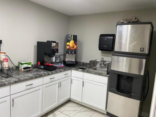 a kitchen with white cabinets and a stainless steel refrigerator at Hibbing Inn and Suites in Hibbing