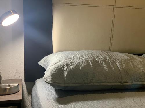 ein Bett mit einer weißen Bettdecke und einer Lampe in der Unterkunft Mexico City MondoMexico Deluxe apartments in Mexiko-Stadt