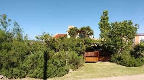 una casa con una valla y árboles en un patio en Morada de encuentro en Capilla del Monte