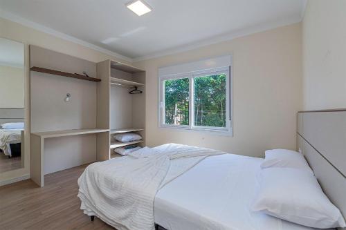 a white bedroom with a bed and a window at Apto Morada Real - Stay House Temporada in Canela