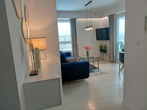 a living room with a blue couch and a table at Apartament z garażem blisko dwóch jezior na Warmii i Mazurach in Biskupiec