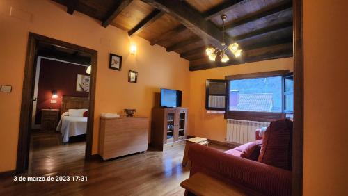 uma sala de estar com um sofá e uma televisão em Apartamentos Rurales Casa Ardaliz em Cangas del Narcea