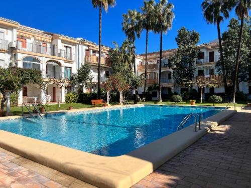 a swimming pool in front of a building with palm trees at Apartamento EL PATIO V in Denia
