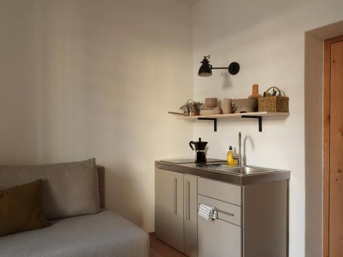 eine Küche mit einem Waschbecken neben einem Sofa in der Unterkunft Urban Inn - Wilten 24/7 in Innsbruck