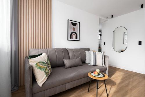 a living room with a gray couch and a table at Apartament Amber - darmowy Parking, ścisłe centrum - by Kairos Apartments in Gliwice
