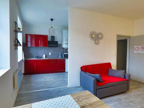 un salon avec un canapé rouge et une cuisine dans l'établissement Apt T2 en RDC style industriel 