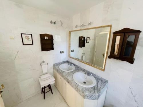 a bathroom with two sinks and a mirror and a stool at Apart Milla de Oro Marbella in Marbella