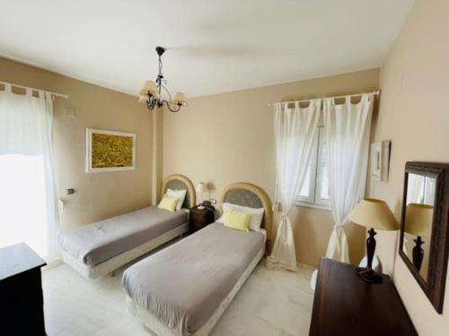 um quarto com 2 camas e uma mesa com um candeeiro em Apart Milla de Oro Marbella em Marbella