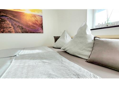 a bedroom with a bed with pillows and a painting at Ring Apartment am Nürburgring in Herresbach