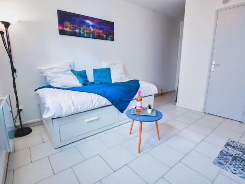 een slaapkamer met een bed met een blauwe deken en een tafel bij Studio style urbain "Cottage de Moissac" in Moissac