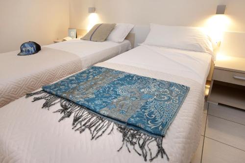 two beds with a blue and white blanket on them at Mariposa Apartments in Bardolino