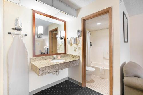 a bathroom with a sink and a toilet and a mirror at OYO Hotel Tulsa International Airport in Tulsa
