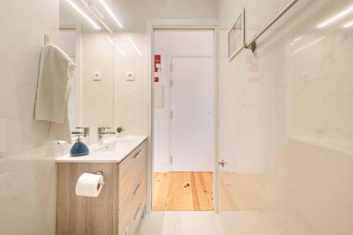 a white bathroom with a sink and a shower at Canto da Praça - No coração do centro de Aveiro in Aveiro