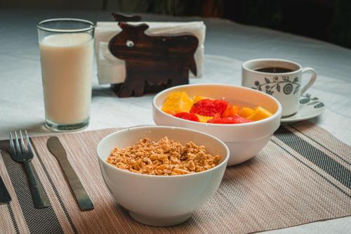 a table with two bowls of cereal and a glass of milk at Hotel El Cocobolo Food&Rest Room 5 B&B WiFi AC Pkg Free Swimmingpool in Liberia