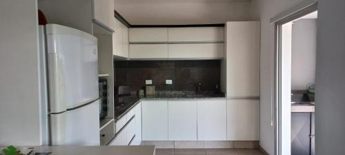 a kitchen with white cabinets and a refrigerator at DOLCE LUNA in Roldán