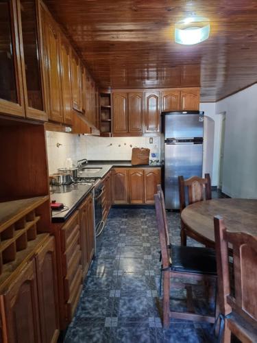 cocina con armarios de madera, mesa y nevera en Casa Nina San Rafael en San Rafael