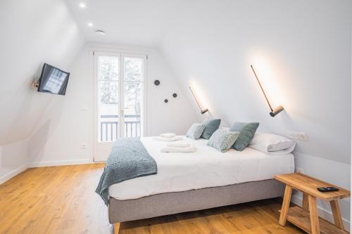 een witte slaapkamer met een groot bed en een tafel bij ARROKAGAIN HOME in Hondarribia