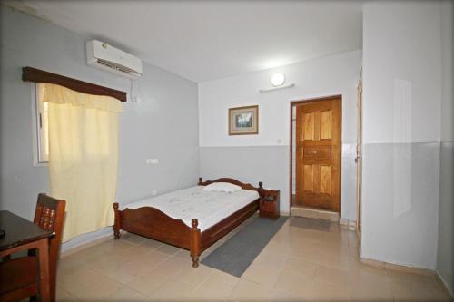 a bedroom with a bed and a wooden door at Amy's Hotel in Lomé