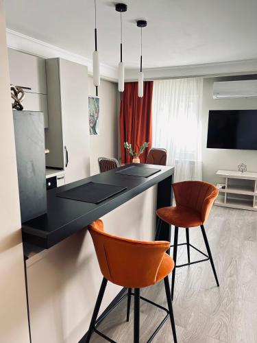 a kitchen with a black counter and orange chairs at Maia Grand Studio Bucharest in Bucharest
