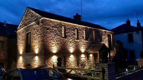 un edificio de ladrillo iluminado con luces encendidas en Swallow Barn en Penrith