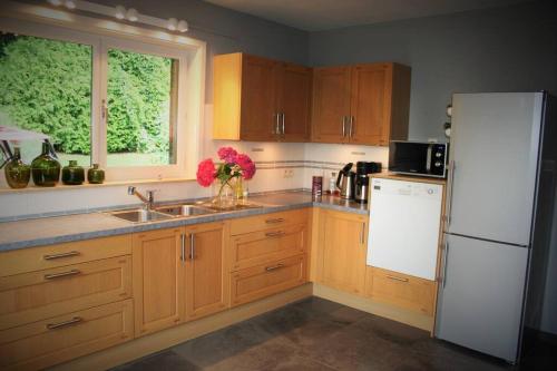 a kitchen with wooden cabinets and a white refrigerator at N°5 Lumen in Flobecq