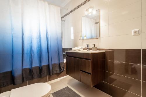 Un baño con inodoro, lavabo y ducha. en The Port Beach House, en Praia da Areia Branca