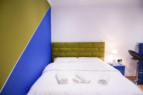 uma cama com toalhas brancas com uma parede azul e verde em City Center 12 - Tirana Way Apartments em Tirana