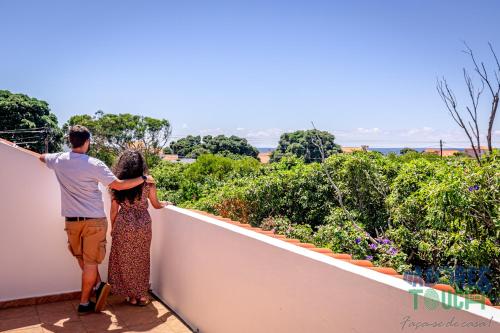 a man and a woman standing on a balcony looking at the ocean at Porto Tranquilo in Porto Martins
