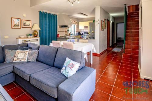 a living room with a blue couch and a kitchen at Porto Tranquilo in Porto Martins