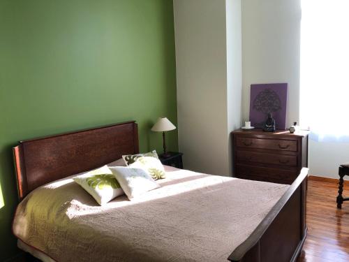 a bedroom with a bed with green walls and a dresser at Le Logis du Gast chambre verte in Le Gast