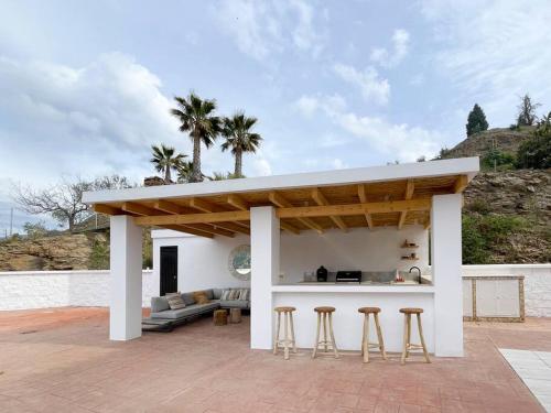 a pavilion with a couch and stools on a patio at Villa Tres Flores in Cómpeta