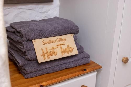a pile of towels on a shelf with a hot tub sign at Swallow Cottage in Bridgend
