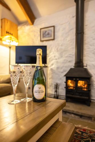 a bottle of wine sitting on a table with two glasses at Swallow Cottage in Bridgend