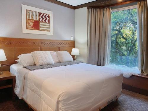 a bedroom with a large white bed and a window at Suíte Completa 3020 no Laje de Pedra Mountain Village Canela e Gramado Serra Gaúcha in Canela