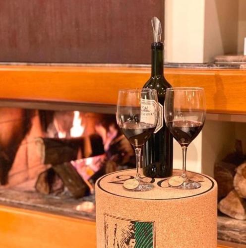a bottle of wine and two wine glasses on a box at Suíte Completa 3020 no Laje de Pedra Mountain Village Canela e Gramado Serra Gaúcha in Canela