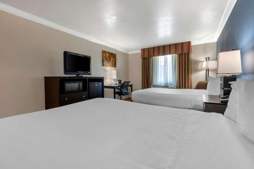 a hotel room with two beds and a flat screen tv at Best Western Colonial Inn in Selma